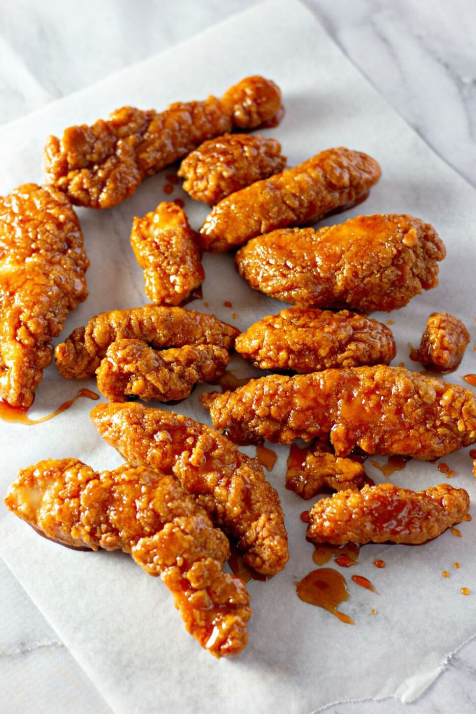 Homemade crispy chicken strips coated in a shiny sweet sauce