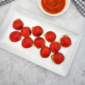 Cream cheese pepperoni appetizers with dipping sauce on the side.