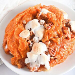 Close-up serving of sweet potato casserole with marshmallows and pecans.
