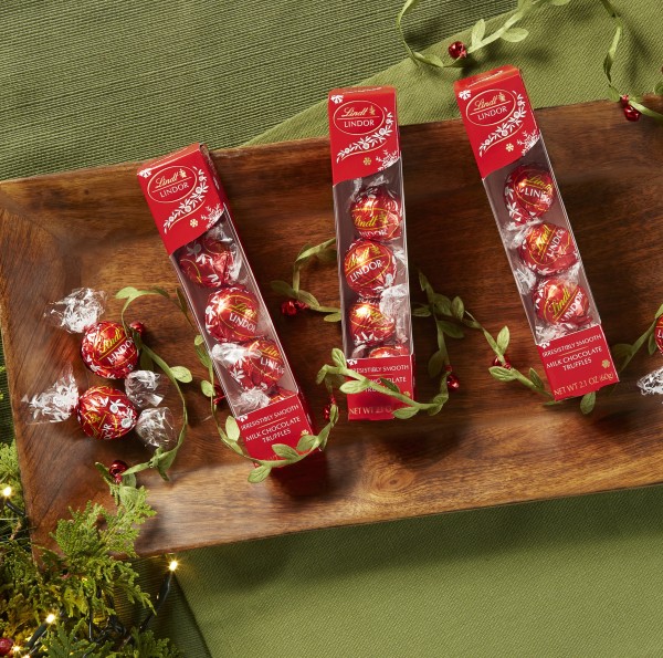 Favor boxes of Lindt Lindor individually wrapped chocolates on a wooden tray