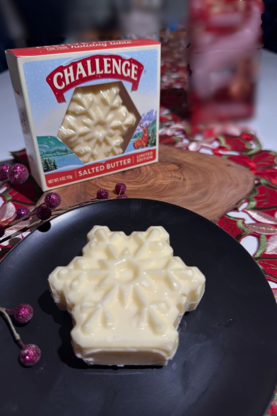 Challenge Butter Snowflake Shape on a black plate next to an unopened package of butter on a holiday table