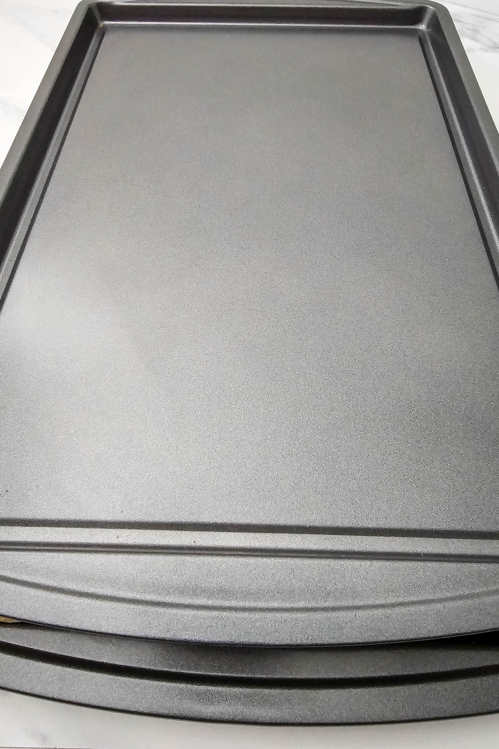 Second sheet pan set on top to press the quesadillas