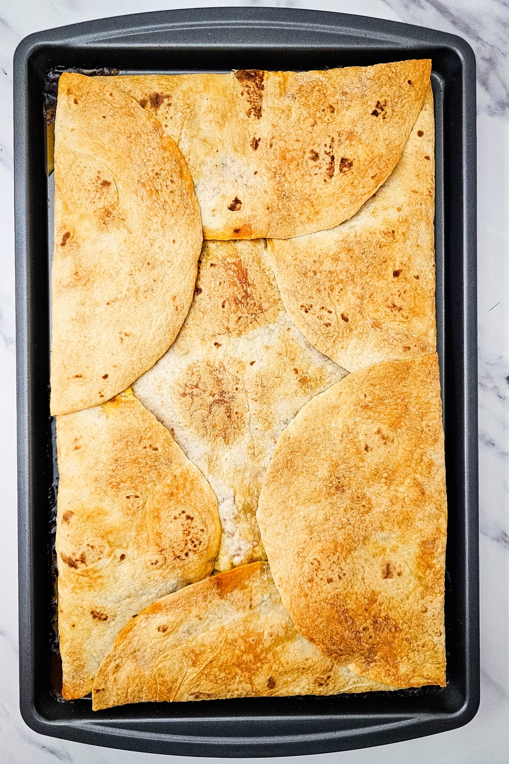 Golden baked sheet pan quesadillas after removing the top pan