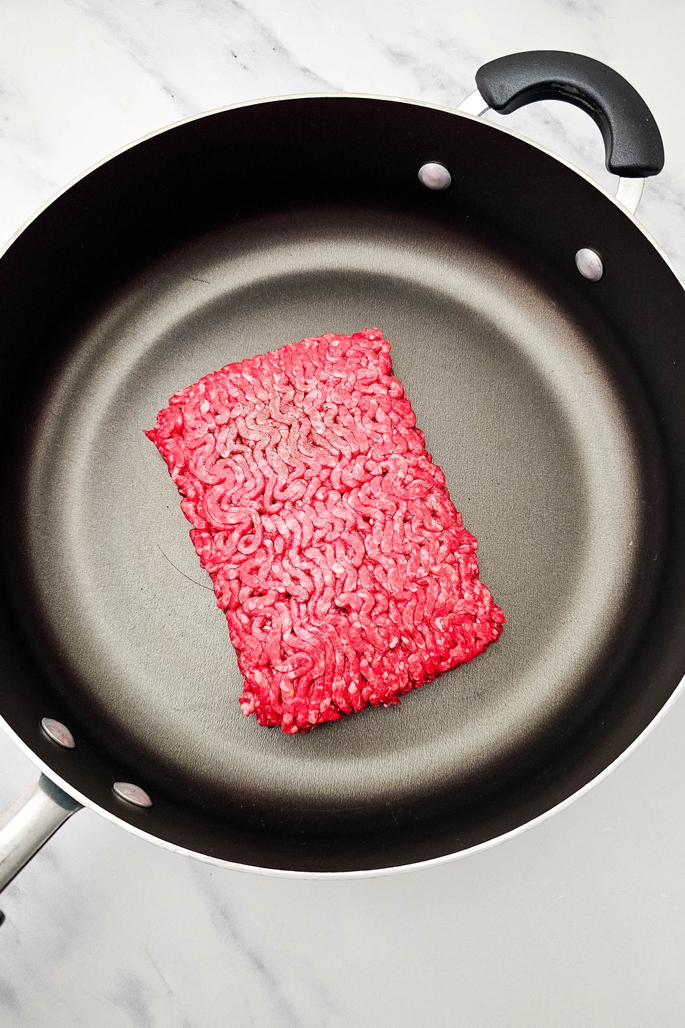 Raw ground beef in a large skillet