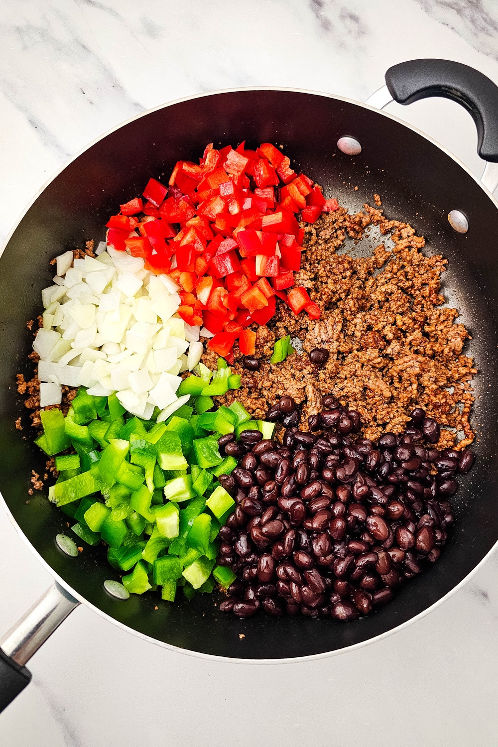 Seasoned beef with diced peppers, onion, and black beans in a skillet
