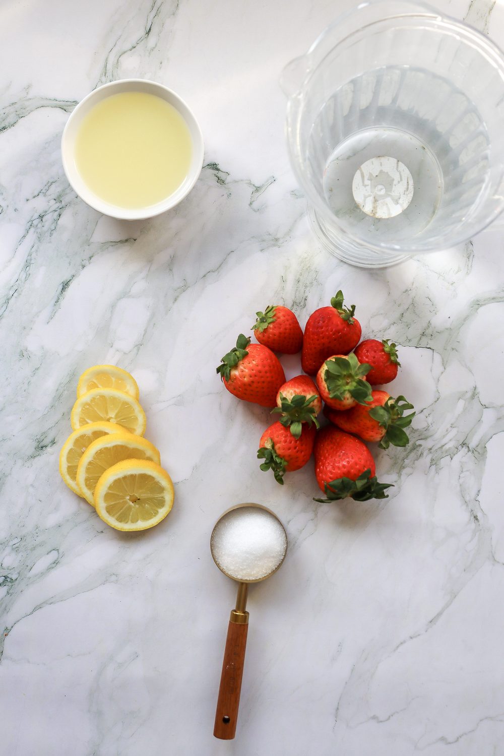 Fresh strawberries, lemons, sugar, and a glass for making 4th of July strawberry lemonade