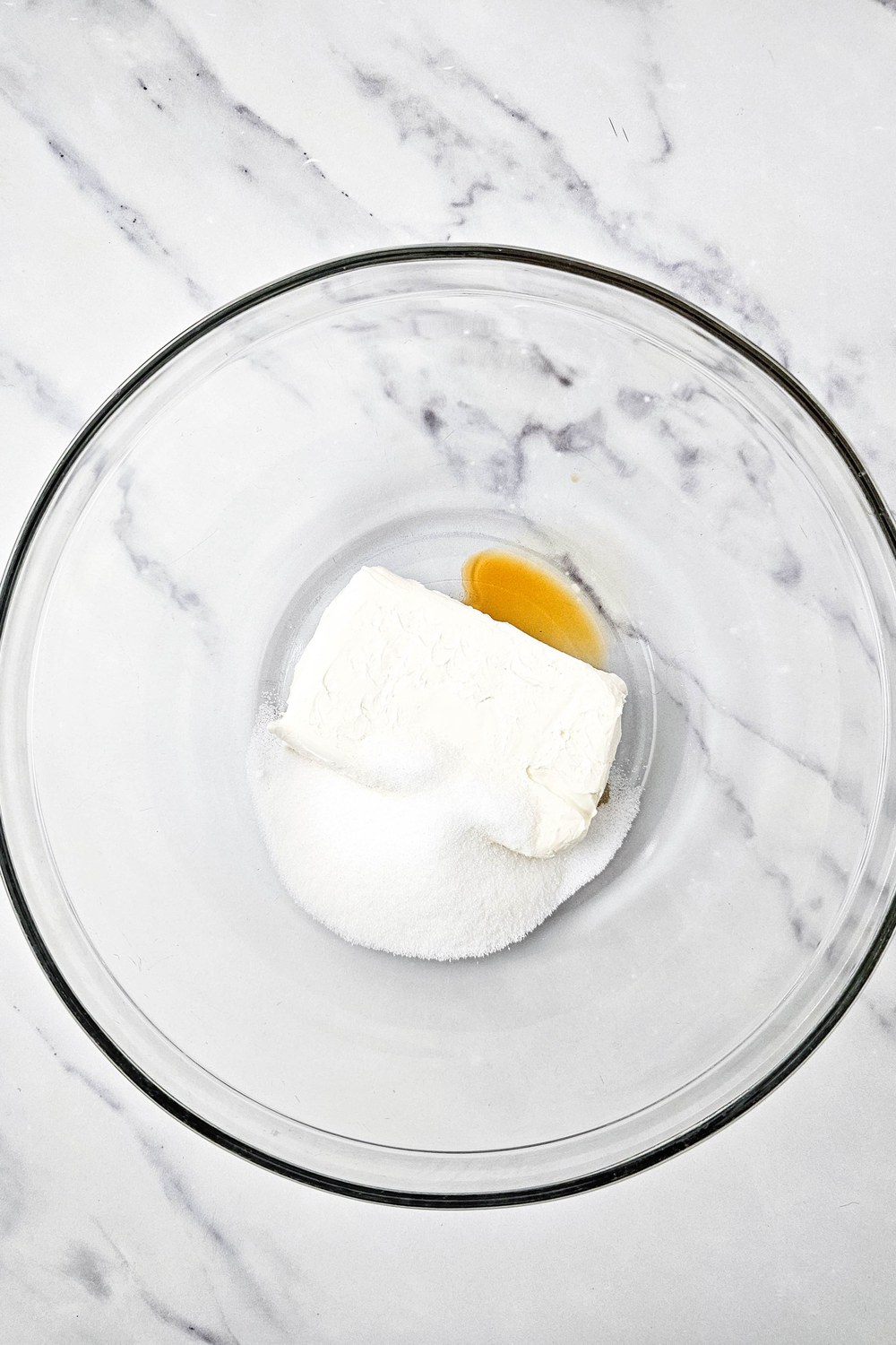 Cream cheese, sugar, and vanilla in a glass mixing bowl before beating, for the cream cheese topping on red, white, and blue fruit pizza