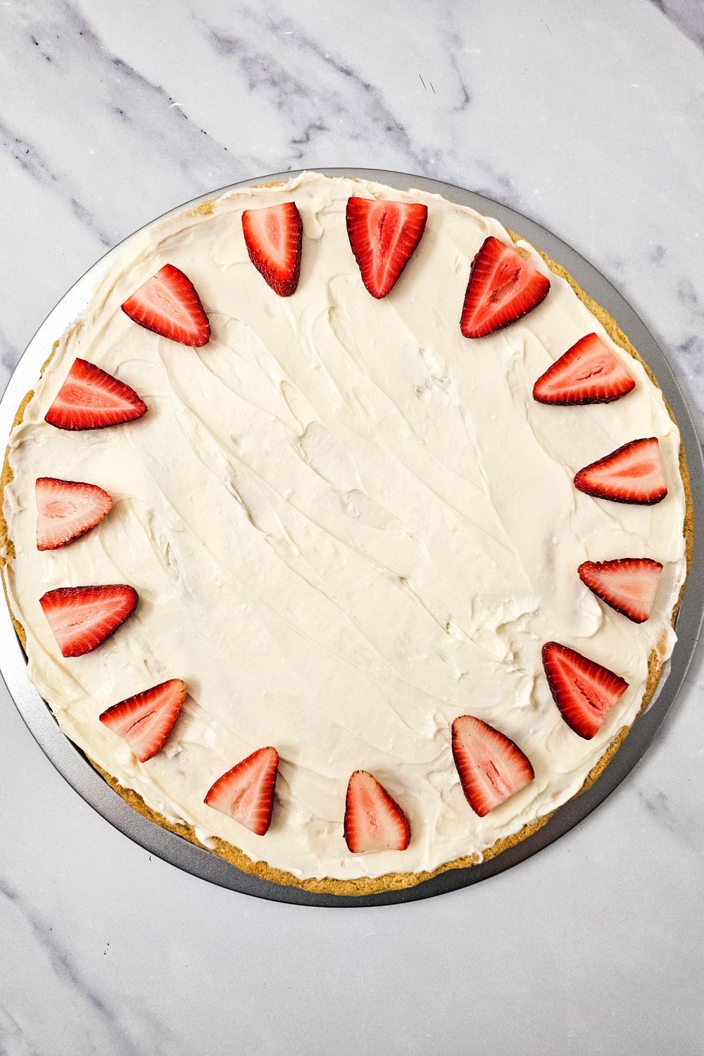 Outer ring of strawberry wedges arranged in a sunburst pattern around the edge of a frosted sugar cookie crust